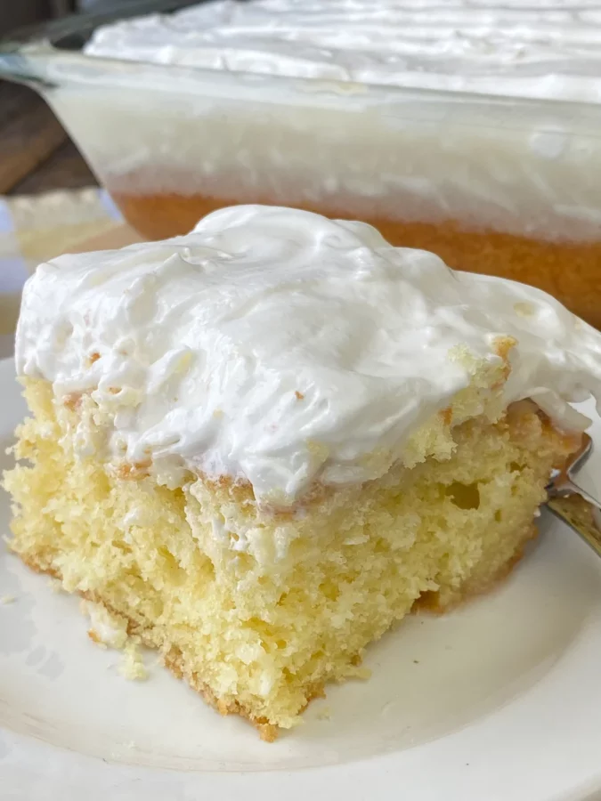 Photo of a piece of Simple Sour Cream Coconut Cake on a white plate - by Plowing Through Life