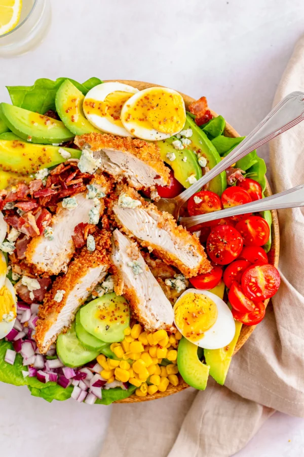 Photo of Chicken Cobb Salad in a bowl with serving spoons - by This Silly Girl's Kitchen