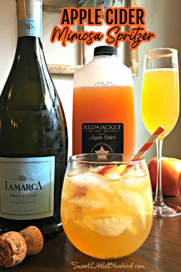 This photo shows a bottle of Prosecco and bottle of apple cider. Next to them are two glasses of apple cider mimosa spritzers. One is served in a champagne glass, the other is served in a short wine glass with no stem.