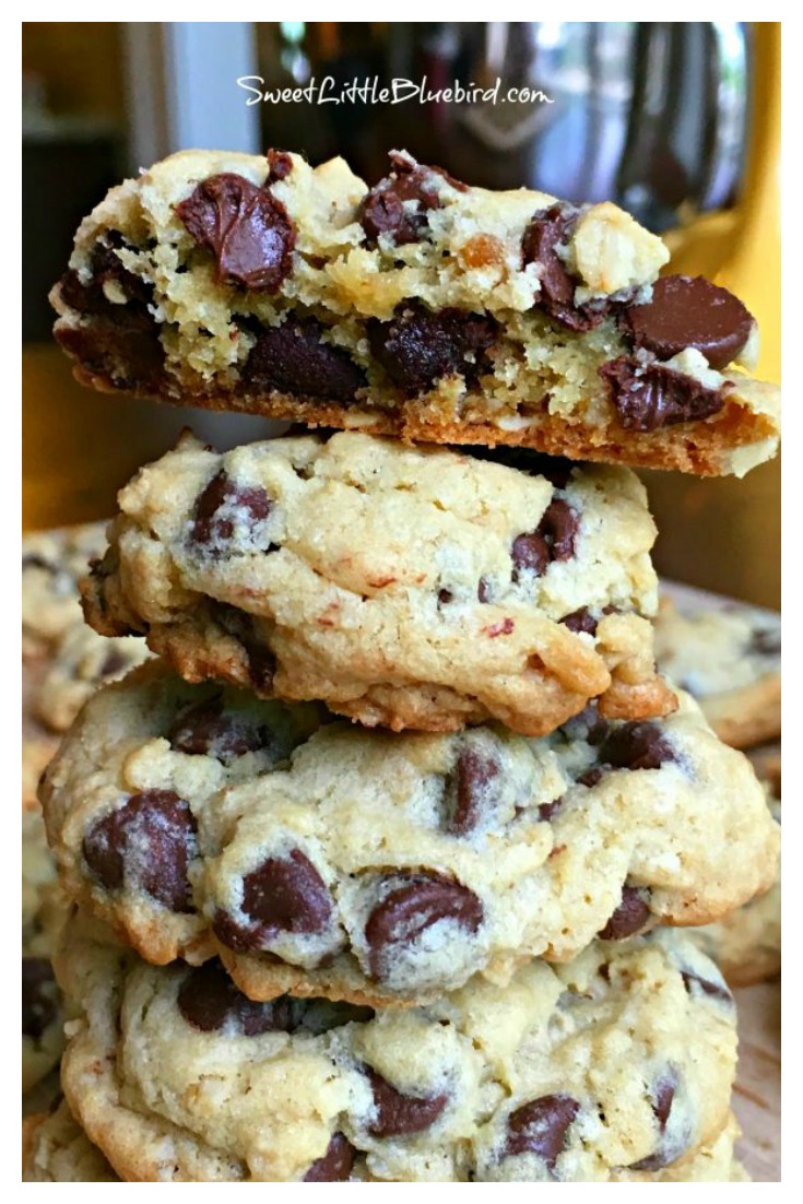 This is a photo of 5 chocolate chip cookies stacked on top of each other. The top cookie is broken is half showing the inside of the cookie. 