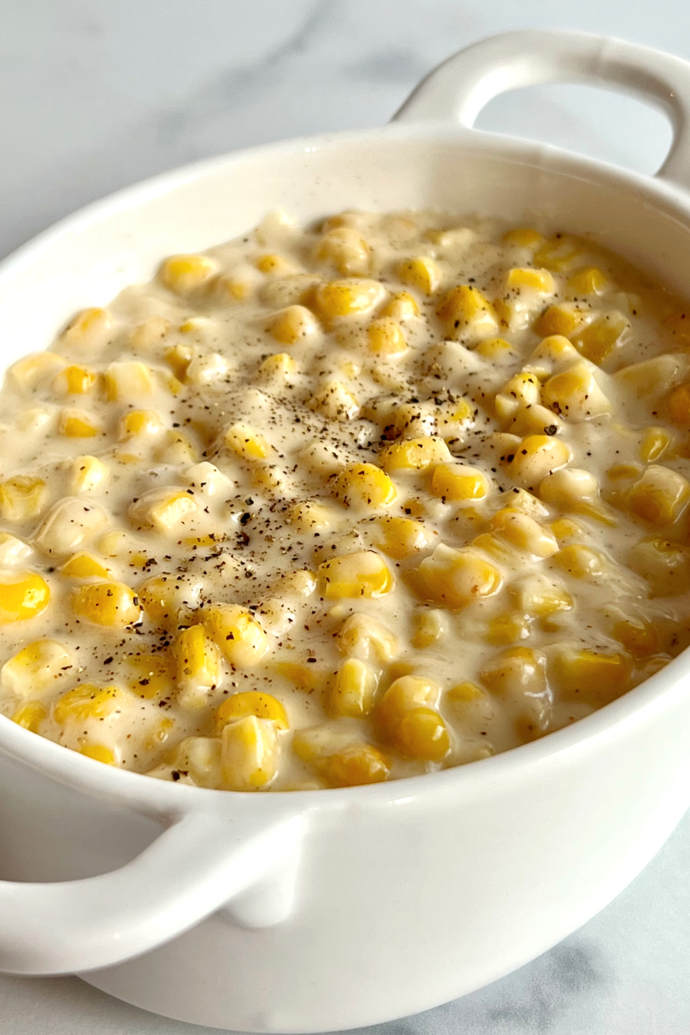 This is a photo showing the creamed corn in a white oval serving dish, ready to eat. 