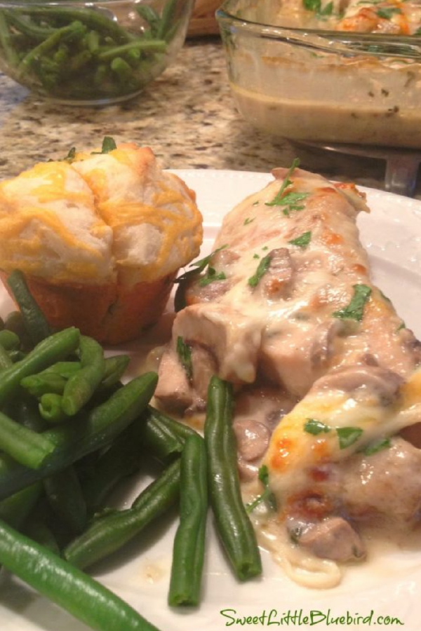 This photo show Chicken Gloria Casserole served on a plate with green beans and a biscuit. 