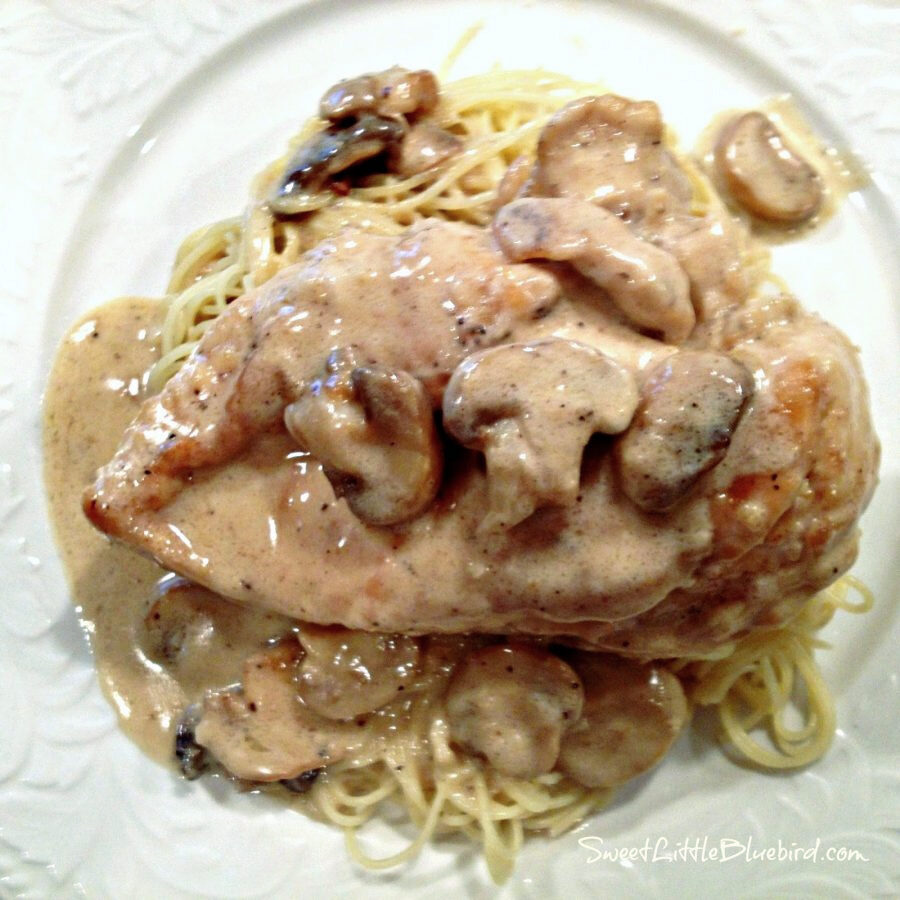 Creamy Lemon Chicken served over angel hair pasta with sauce on a white plate.