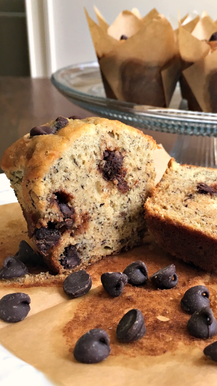 A CHOCOLATE CHIP BANANA MUFFIN cut in half with chocolate chips sprinkled around the muffin. 