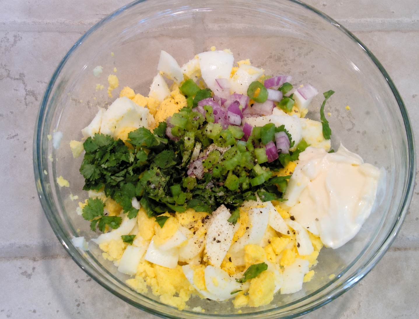 Cilantro Lemon Lime Egg Salad in a clear glass mixing bowl on kitchen counter.