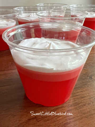 Photo of Copycat Jello 1-2-3 Layered Dessert using Strawberry Jello in a clear plastic cup.