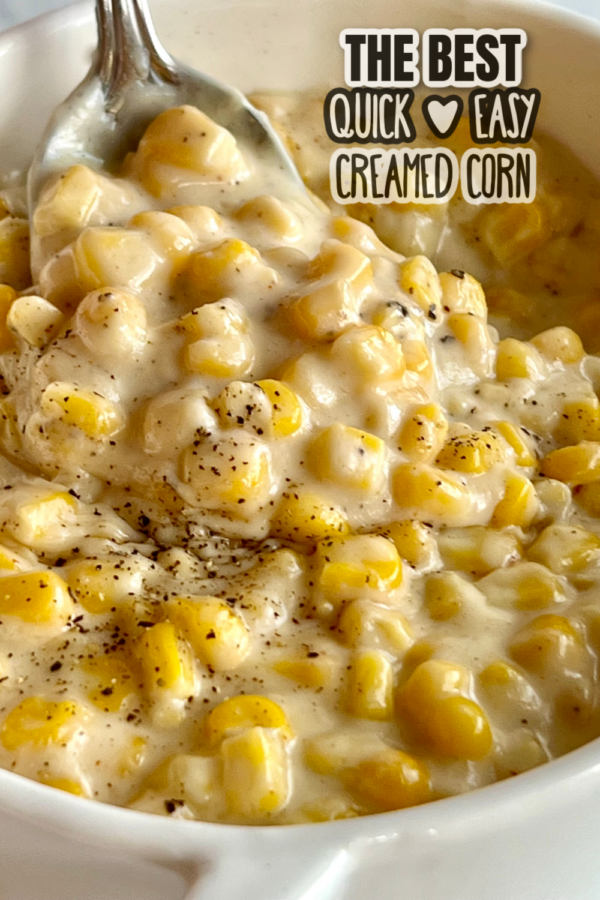 This is a photo of Homemade Creamed Corn served in a white serving dish with a spoon.