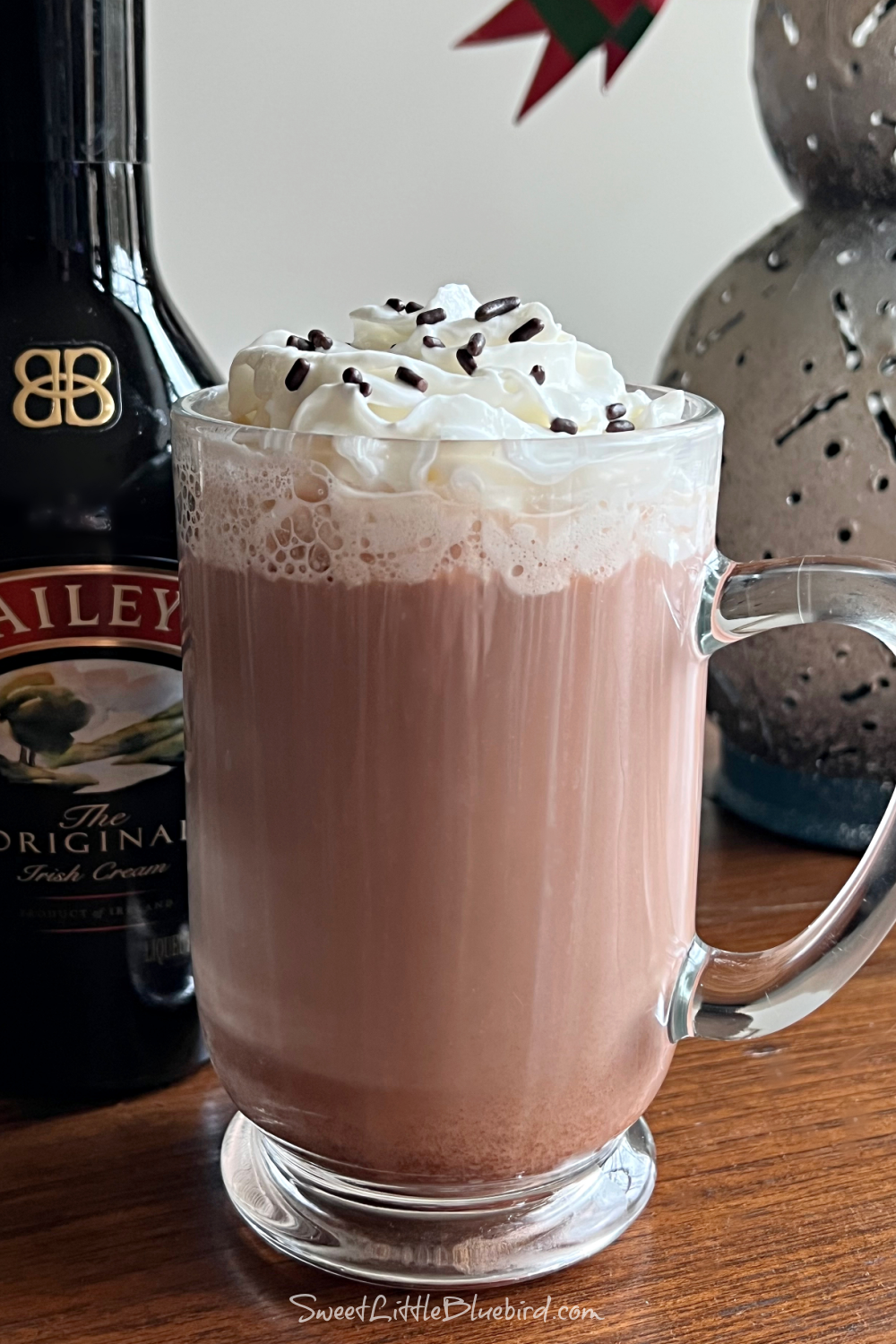 This photo shows a Dirty Snowman cocktail served in a clear mug glass, topped with whipped cream and chocolate sprinkles.