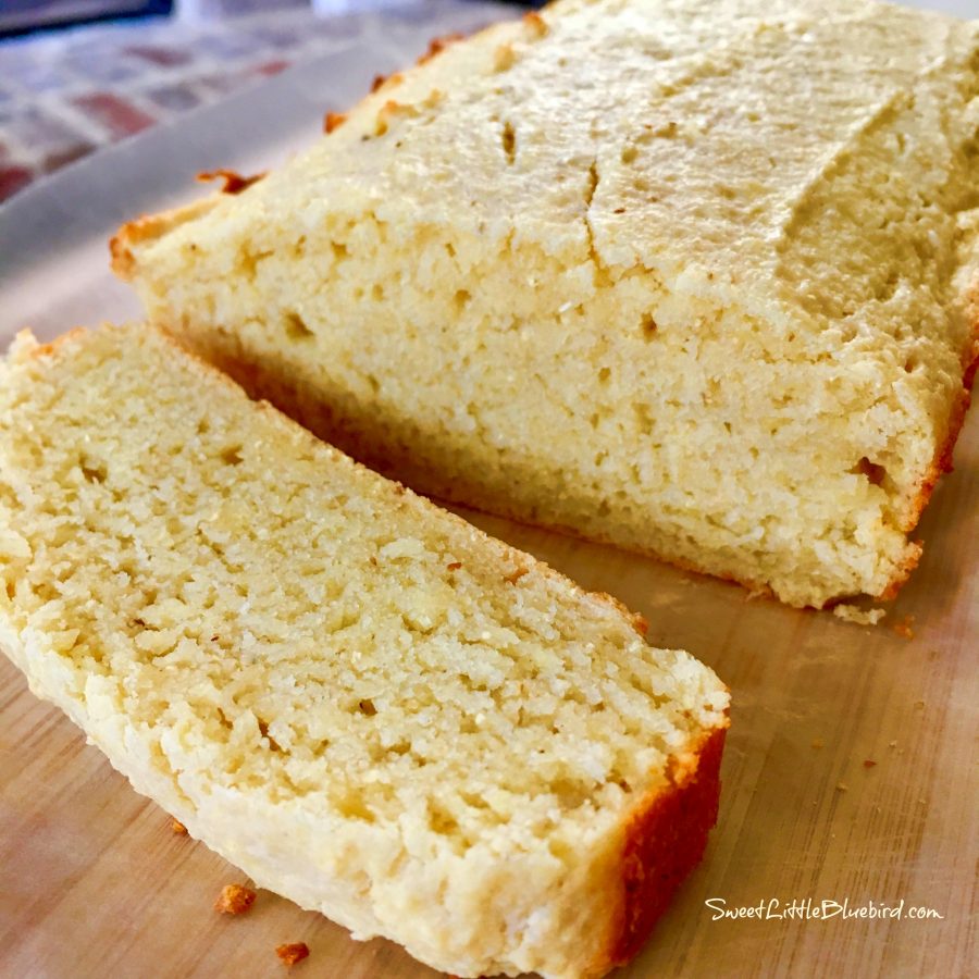 This photo shows a piece of Amish Sour Cream Cornbread cut from the loaf on a cutting board. 