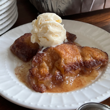 Crescent Roll Peach Dumpling on a plate with a scoop of vanilla ice cream on top.
