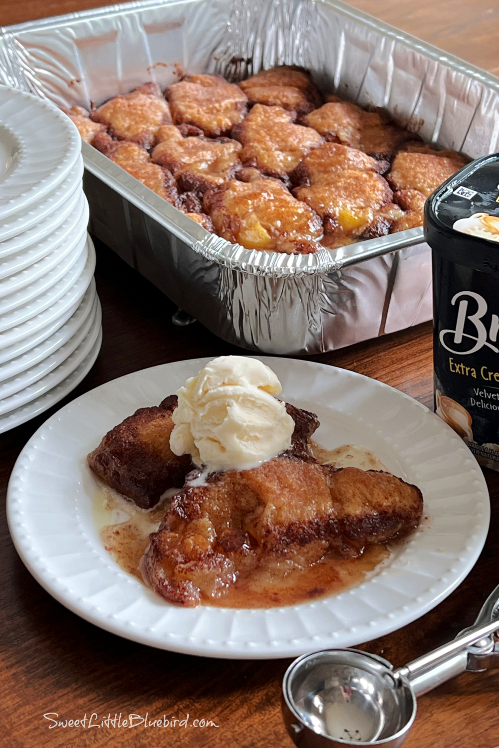 This photo shows 2 peach dumplings on a plate with a scoop of vanilla ice cream on top. 