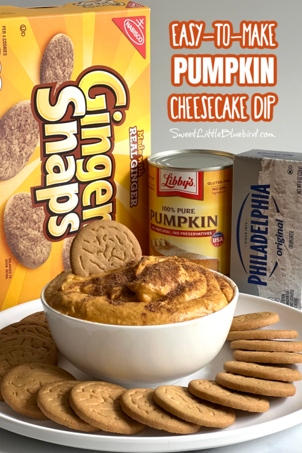 This photo shows pumpkin cheesecake dip served in a white bowl with a plate ginger snap cookies. Behind the bowl is a box of gingersnap cookies, a can of pumpkin purée and a box of cream cheese.