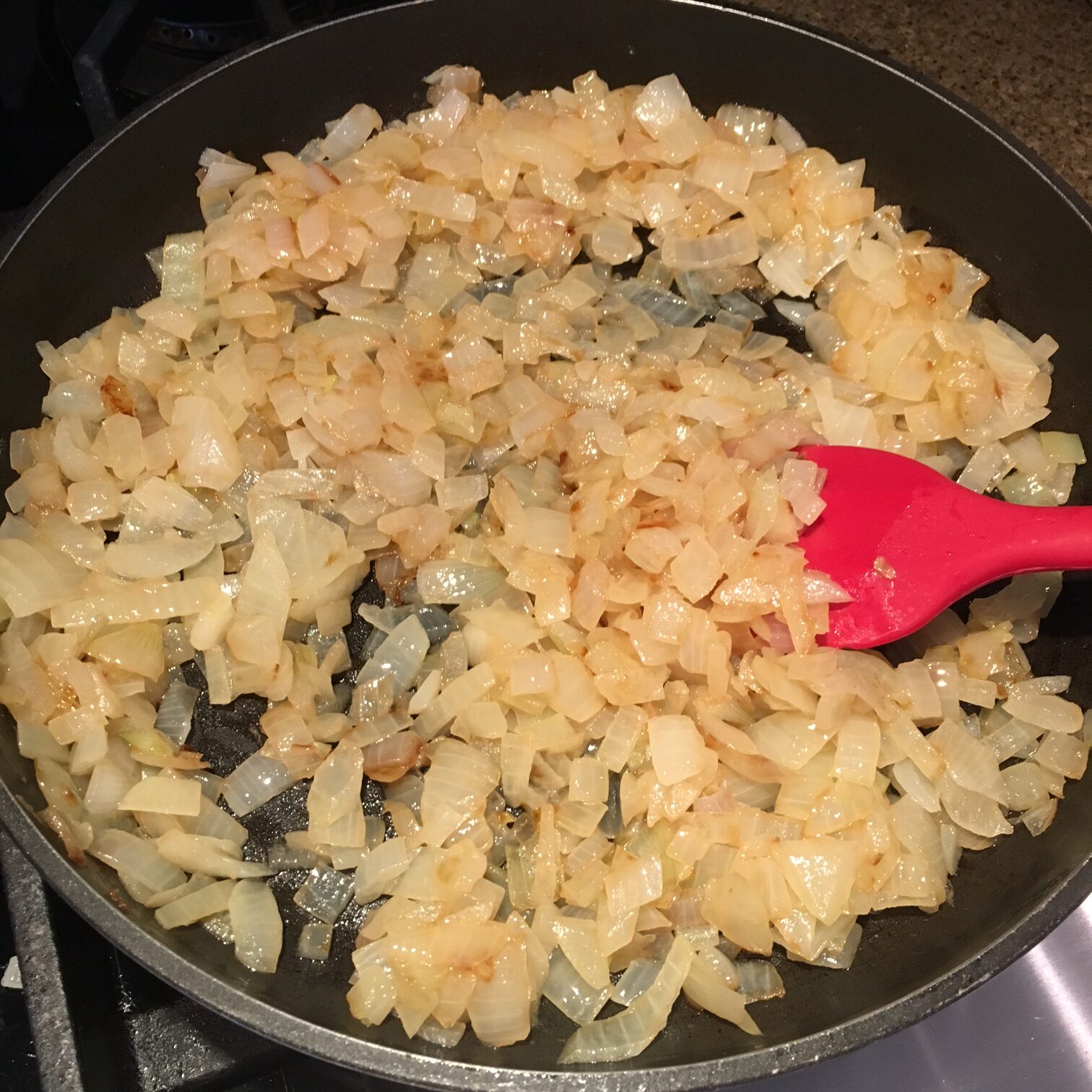 Onions being sautéd on the stove in a pan.