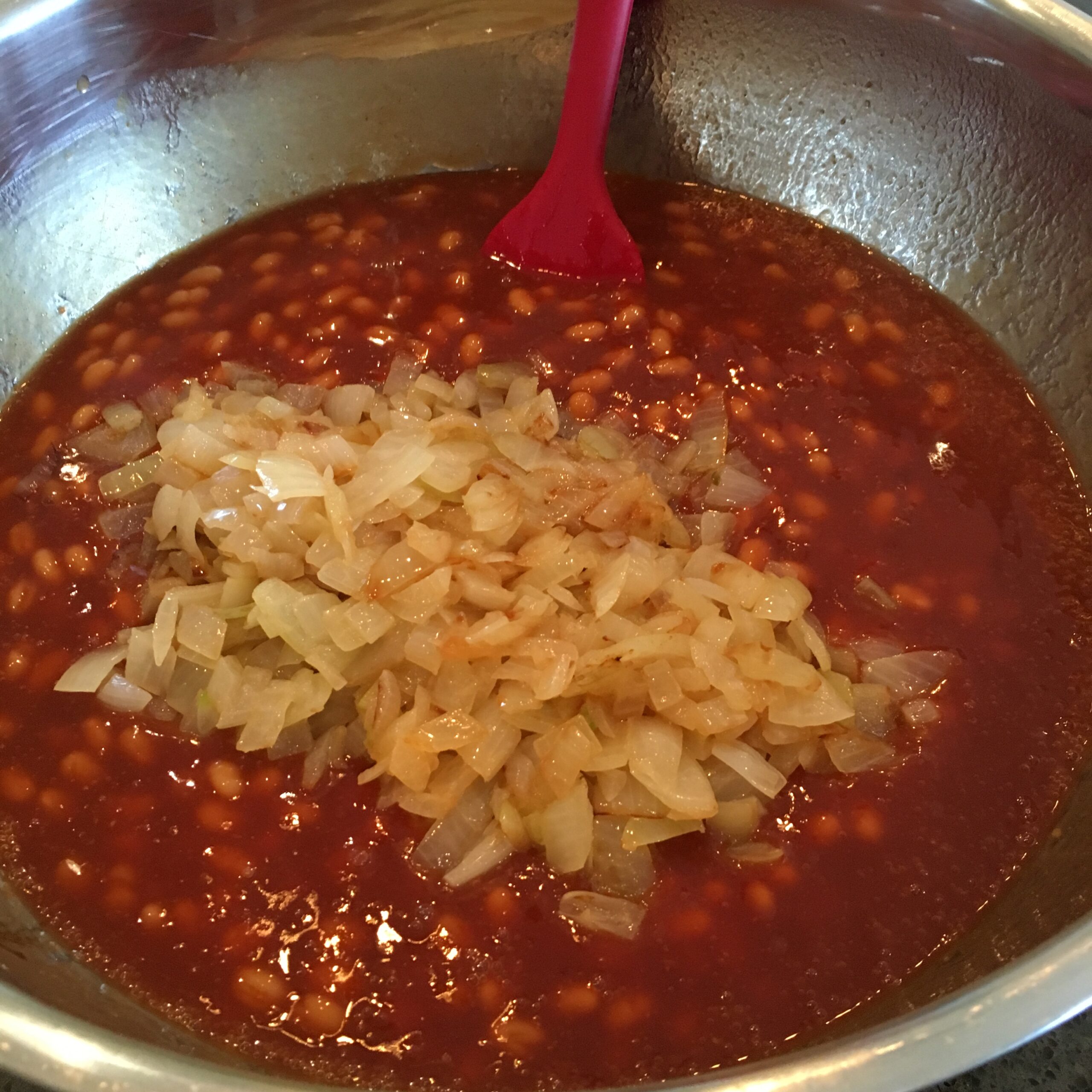 Mixing the beans and sautéd onions in a bowl.