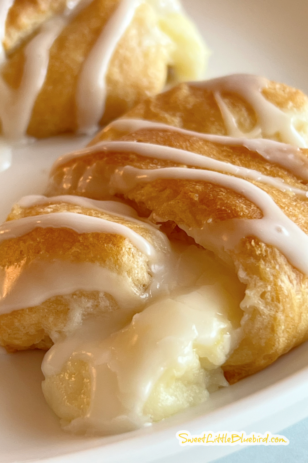 This is a close up photo of a Lemon Cheesecake Crescent Roll on a white plate, showing the filling. 