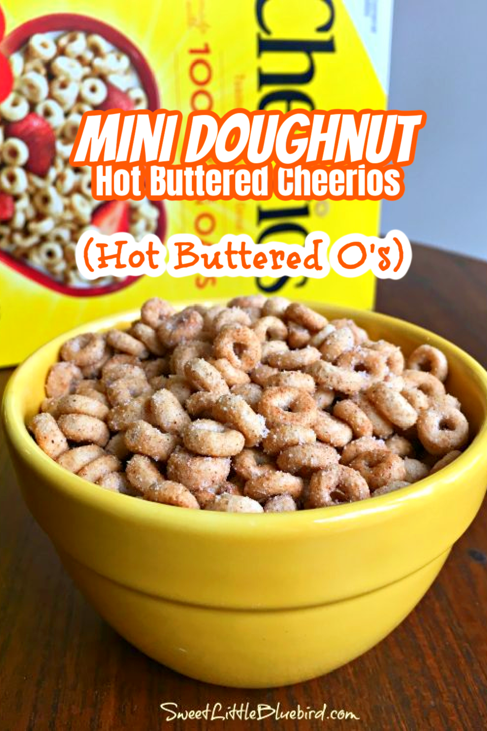 This is a photo of Mini Doughnut Hot Buttered Cheerios served in a yellow bowl with a box of Cheerios in the background.