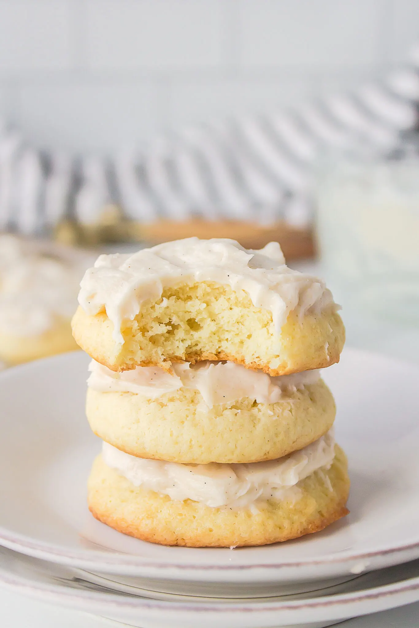 This photo shows 3 Old-Fashioned Sour Cream Cookies stacked on top of each other, with the top cooking showing the onside from a bite taken from the cookie. 