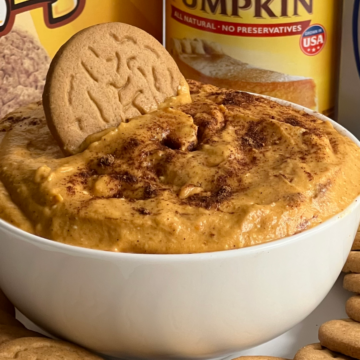 This photo shows Pumpkin Cheesecake Dip served in a white bowl with gingersnap cookies.