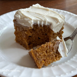 A photo of a piece of Pumpkin Crazy Cake on a white plate with a fork filled with cake ready to eat.