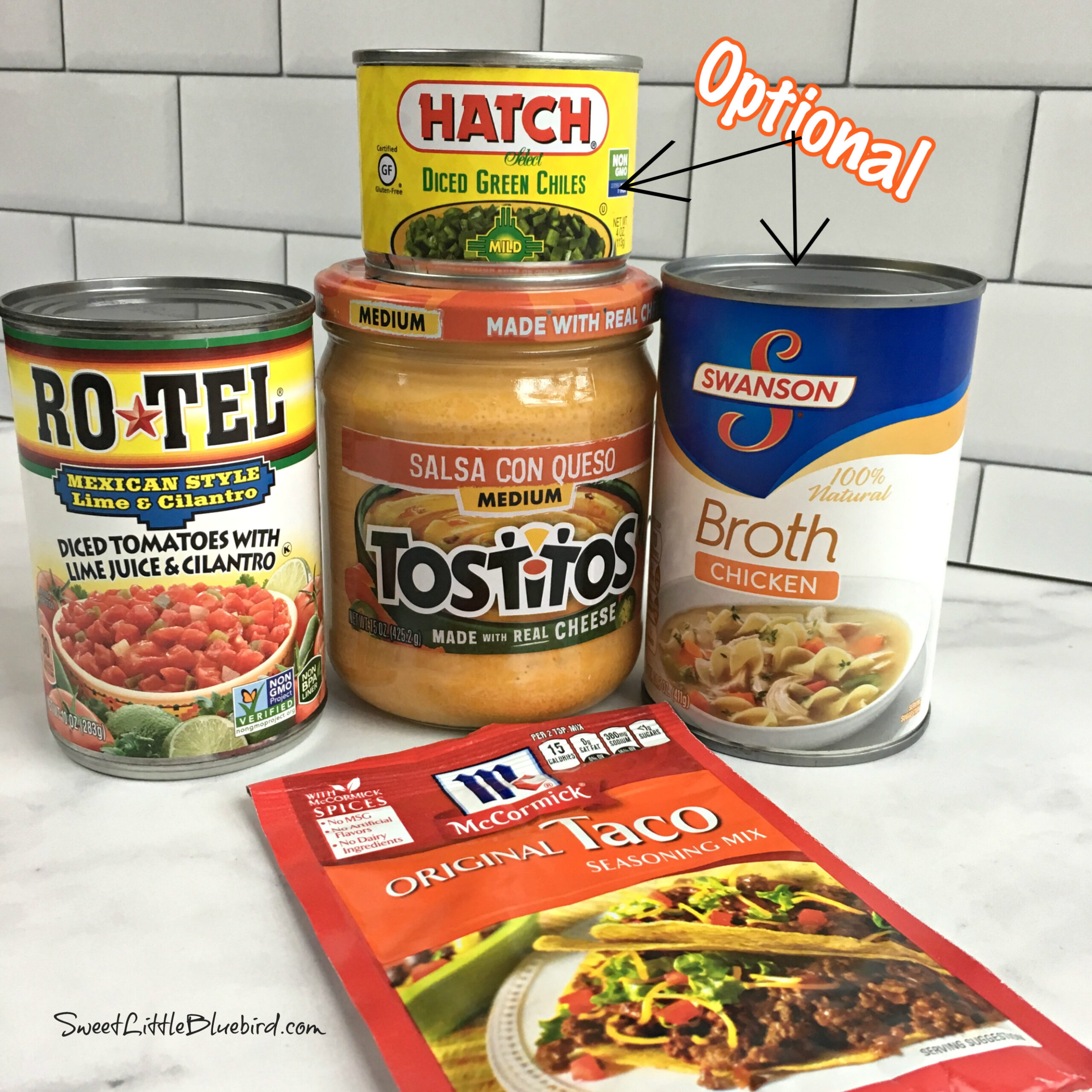 This is a showing the original recipe ingredients. The photo shows a packet of taco seasoning, a jar of queso, a can of Rotel and a can of diced green chiles and a can of chicken broth. 