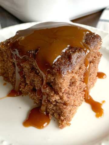 This is a photo of a piece of snickerdoodle crazy cake topped with caramel sauce, served on a white plate.