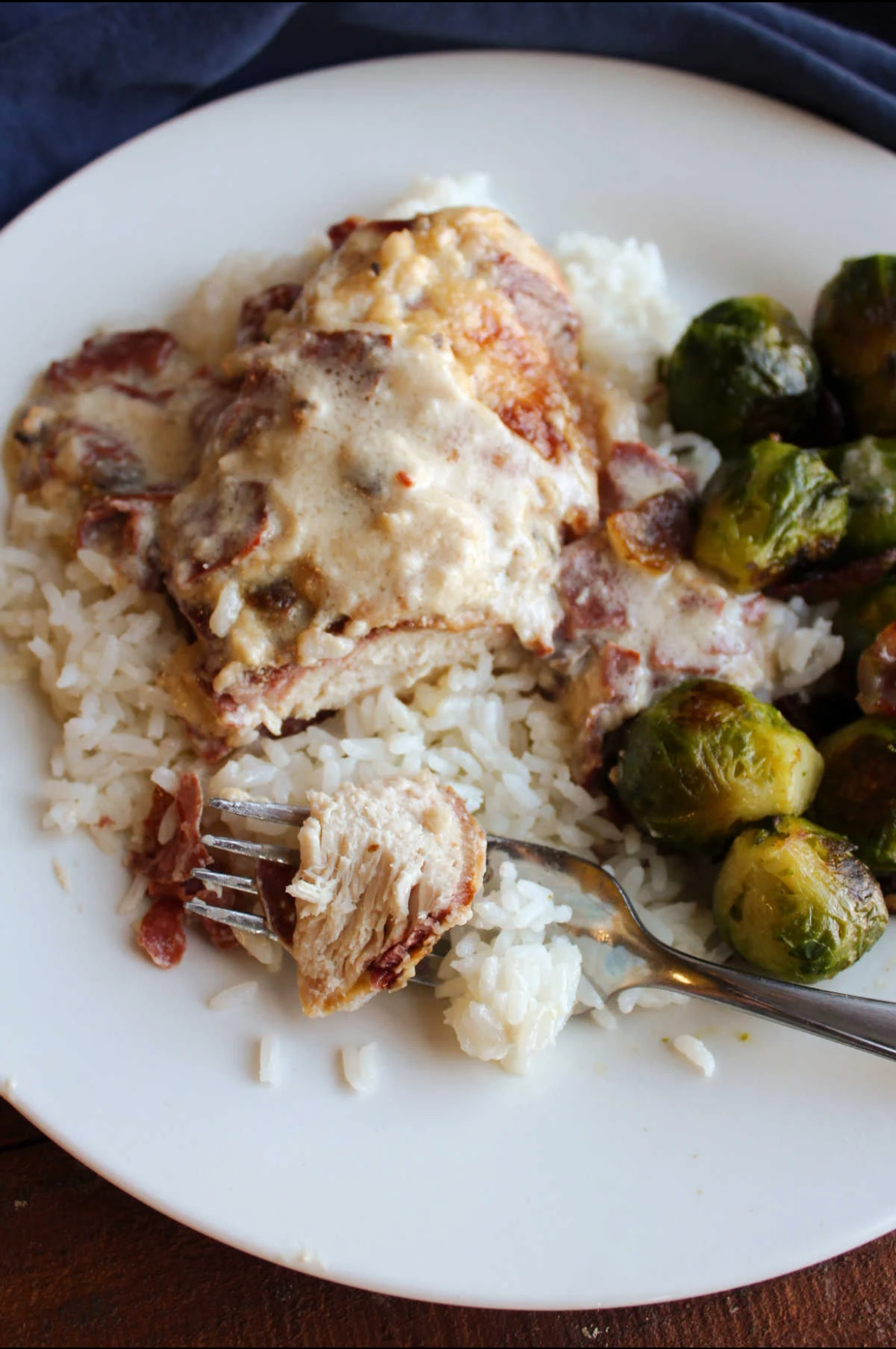 A piece of Grandma's Party Chicken on plate with white rice and Brussels Sprouts. 