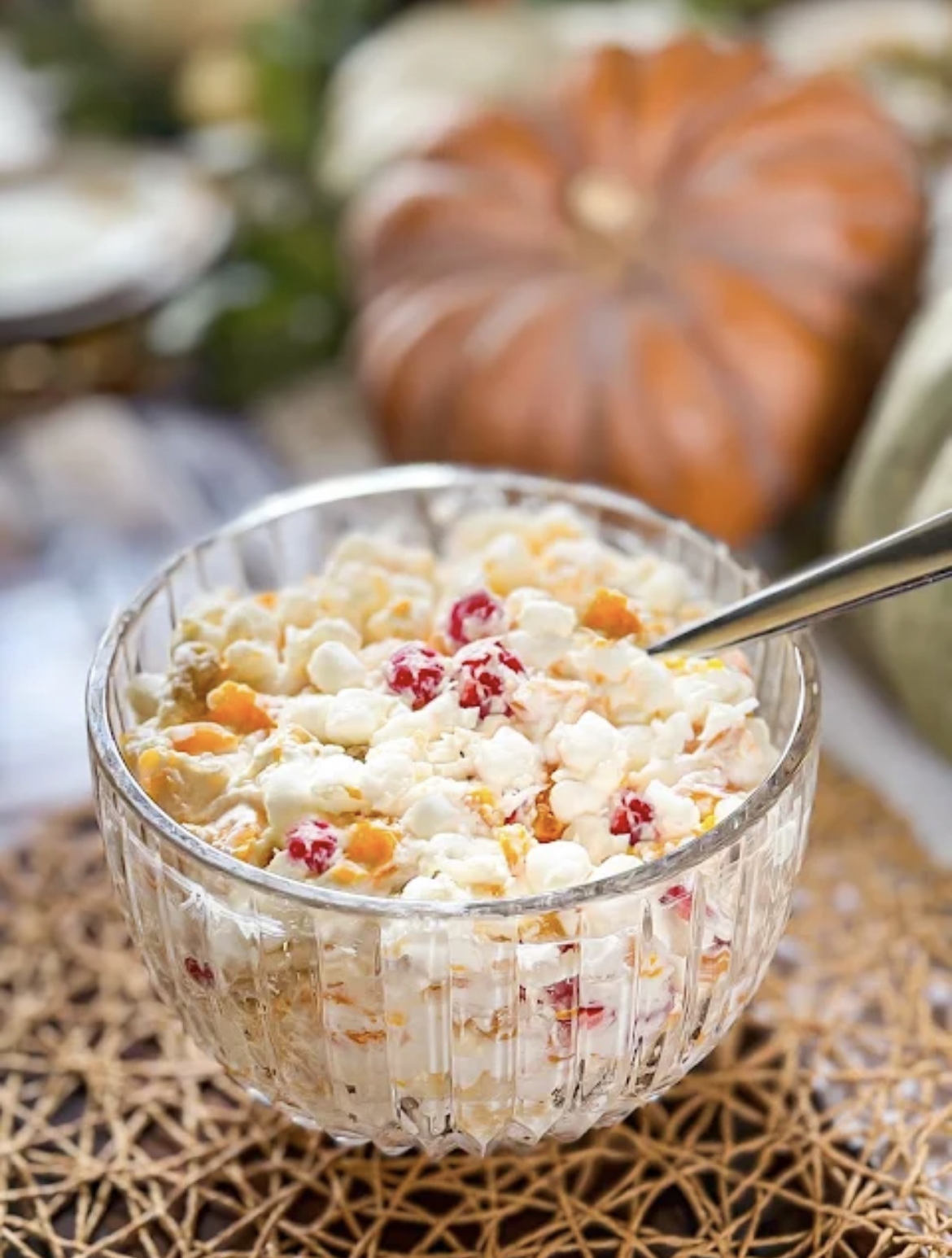 This image shows 24 Hour Fruit Salad in a clear glass serving dish with a spoon. 