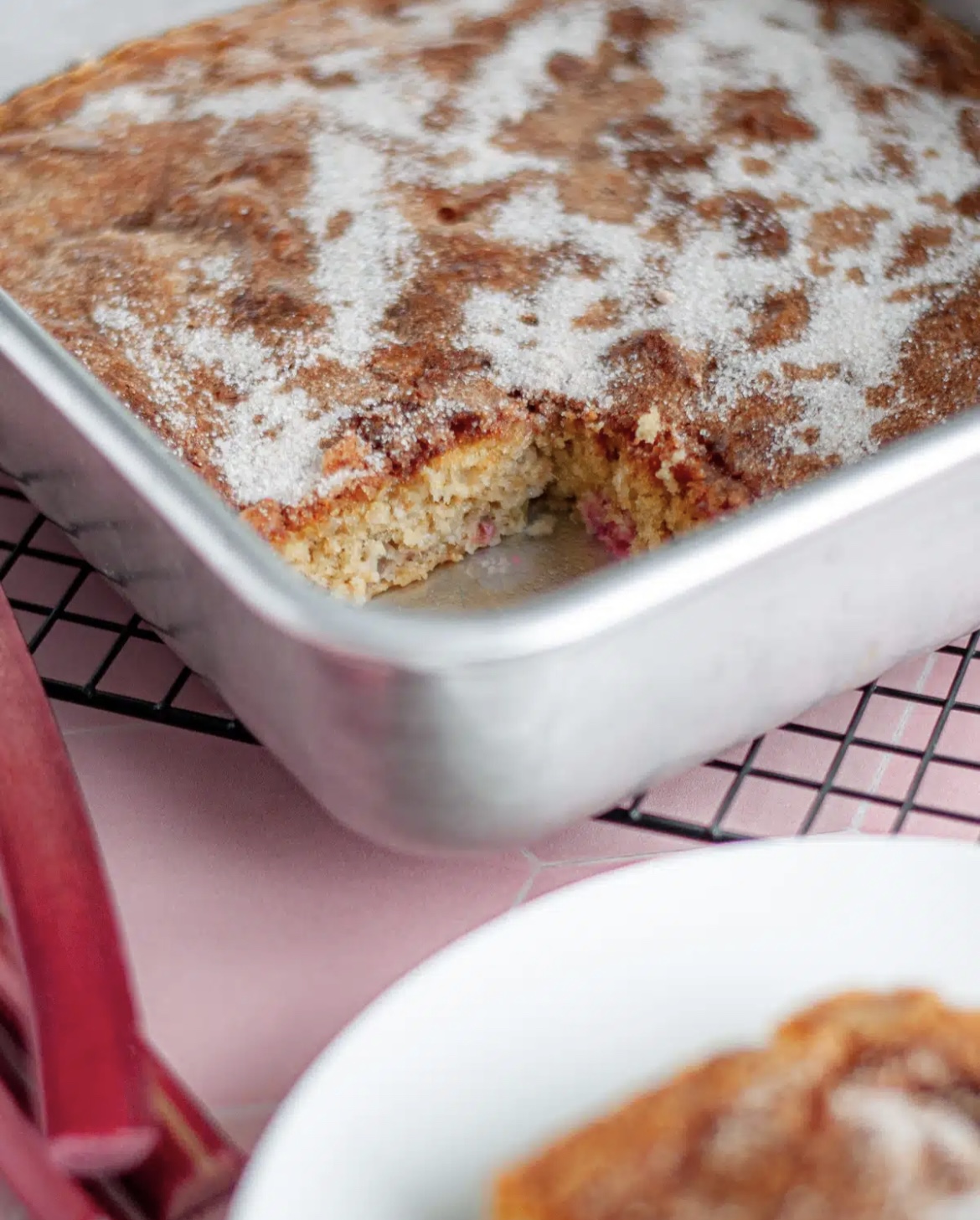 This image shows Rhubarb Cake in a baking pan, ready to serve. 