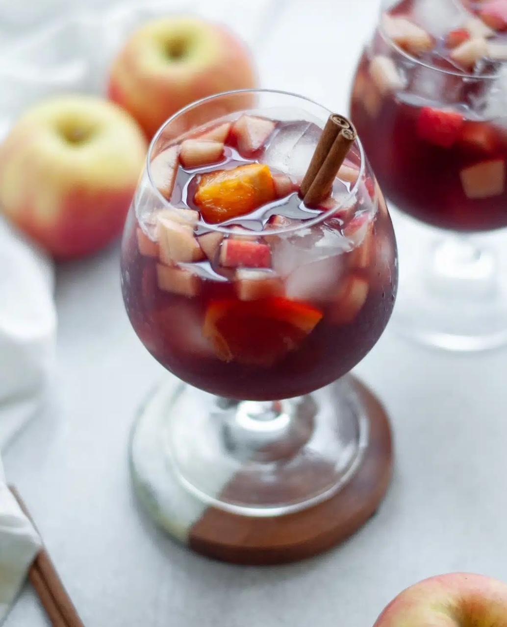 Fall Sangria Recipe (Red Wine) Two clear, short base wine glasses filled with red wine sangria and a cinnamon stick.