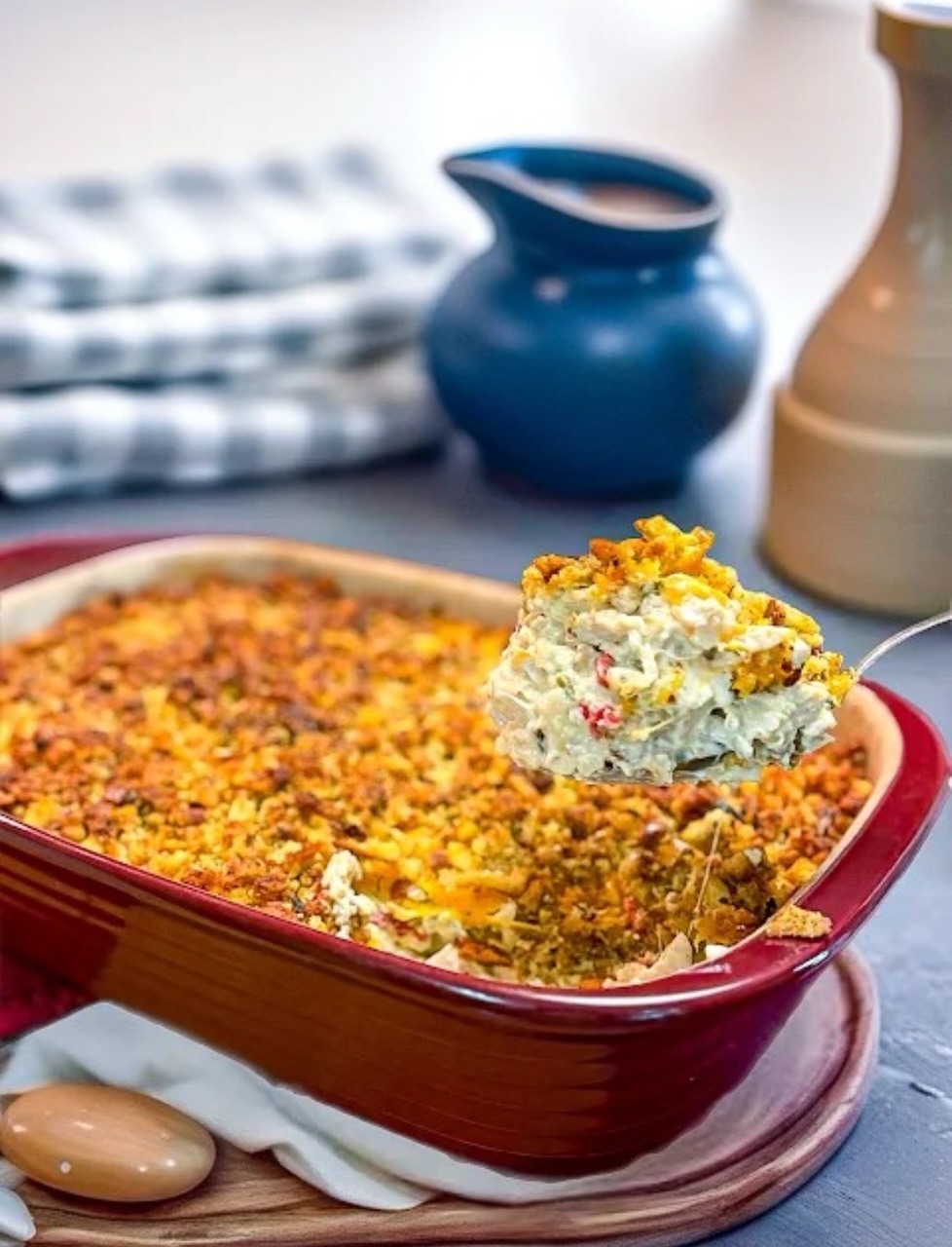 Chicken Terrific Casserole in a cranberry red baking dish with s spoon, ready to serve. 