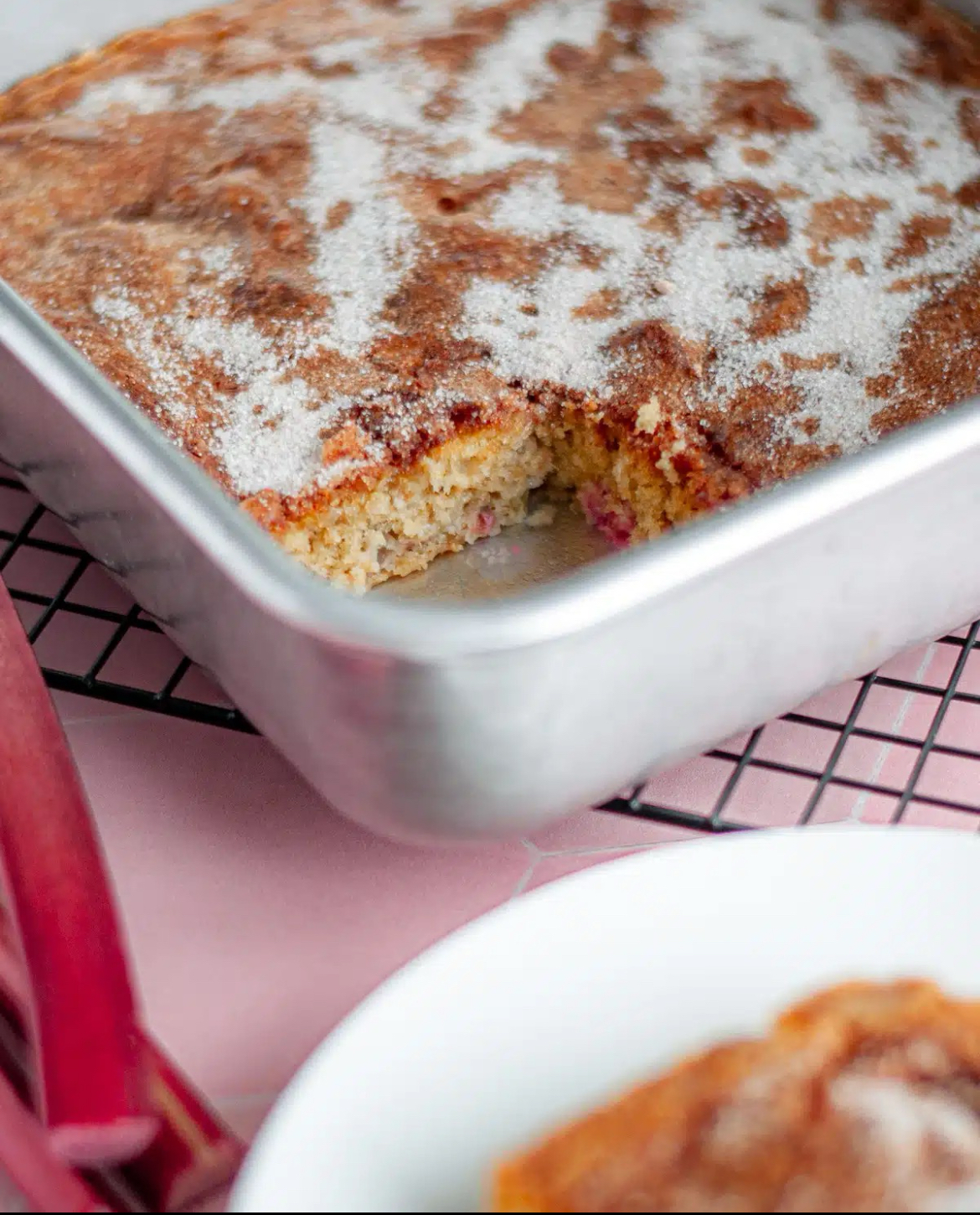 Rhubarb Cake Rhubarb Cake in a metal baking pan with a piece served on a plate.