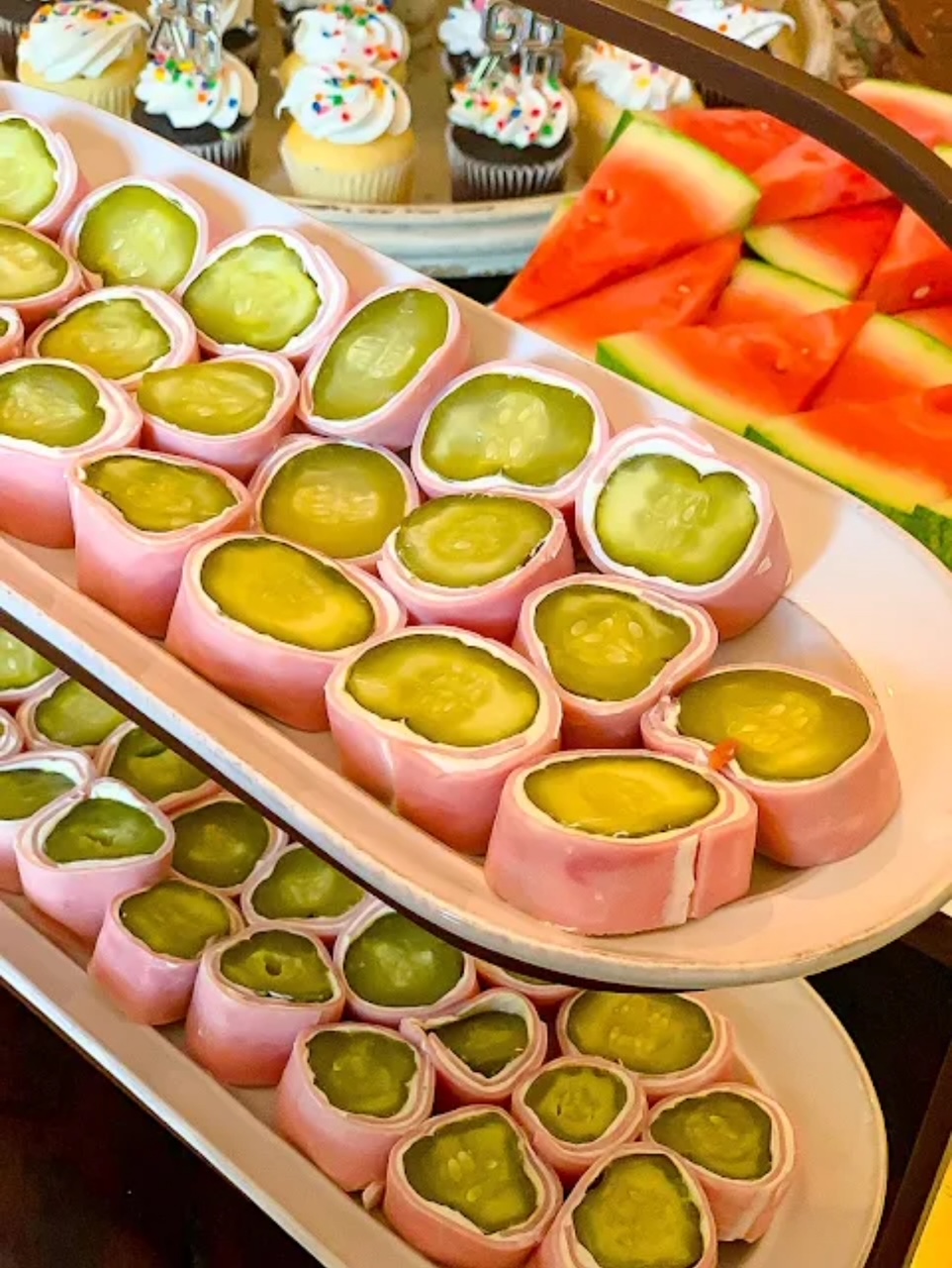 Ham and Dill Roll UPs served on two white oval serving plates on a stand - stacked on top of each other. 