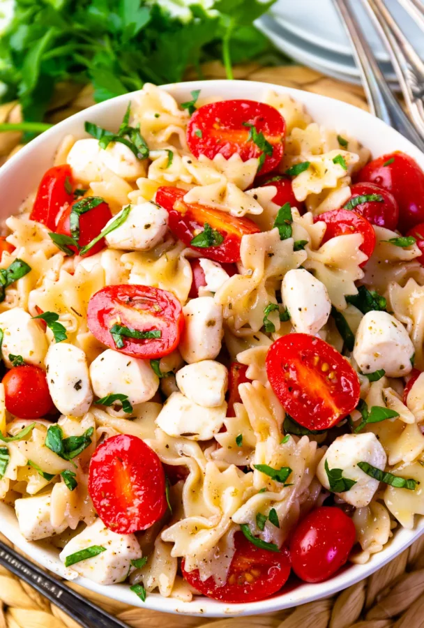 Photo of Caprese Pasta Salad served in a white bowl.