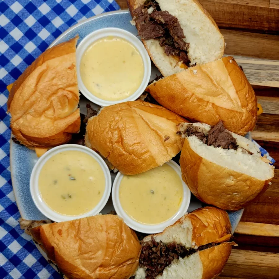 This is a photo of Cowboy Beef Dips cut in half served on a plate with dipping sauce.