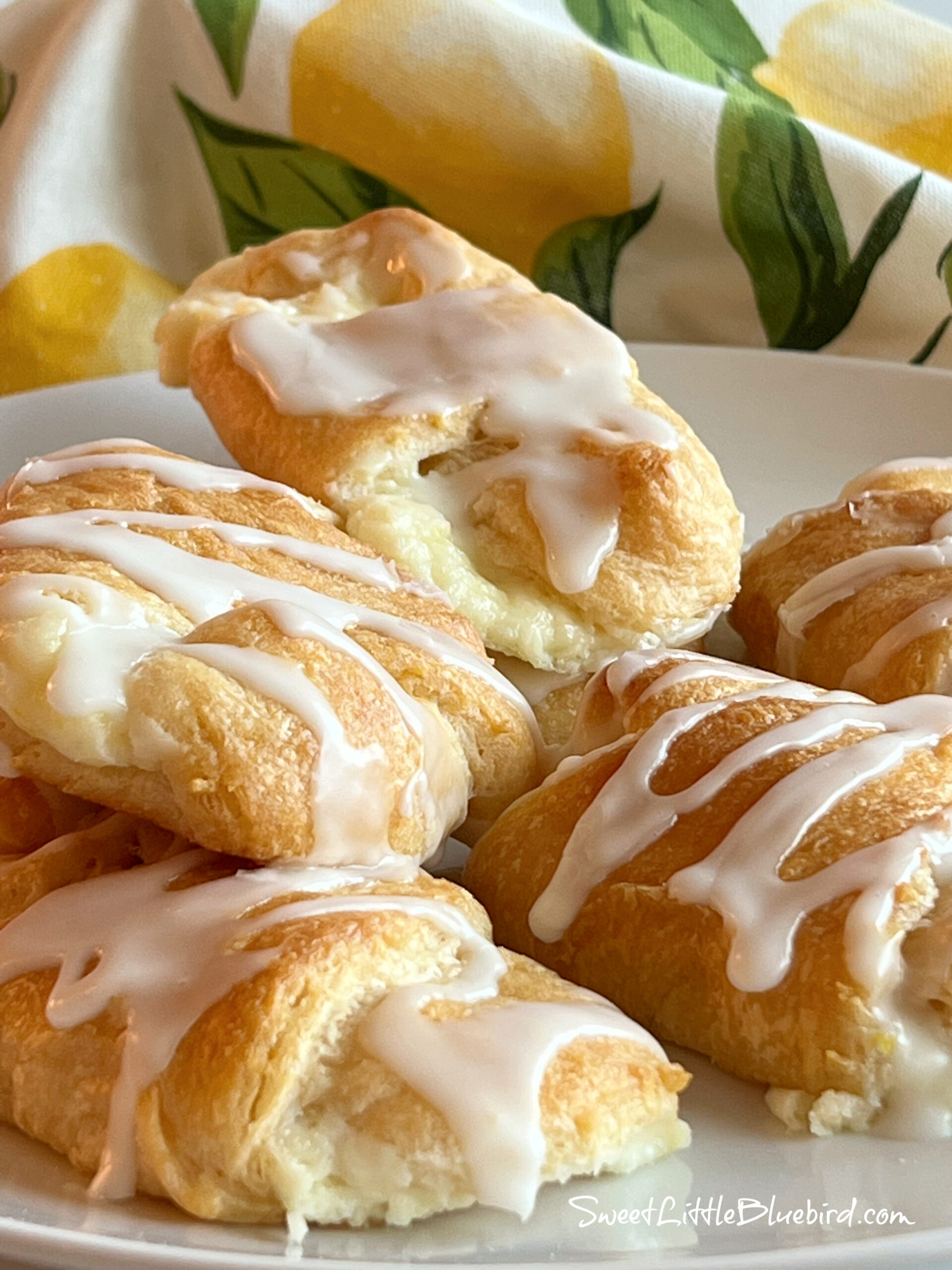 This is a photo of the Lemon Cheesecake Crescent Rolls served on a white plate, stacked on top of each other. 