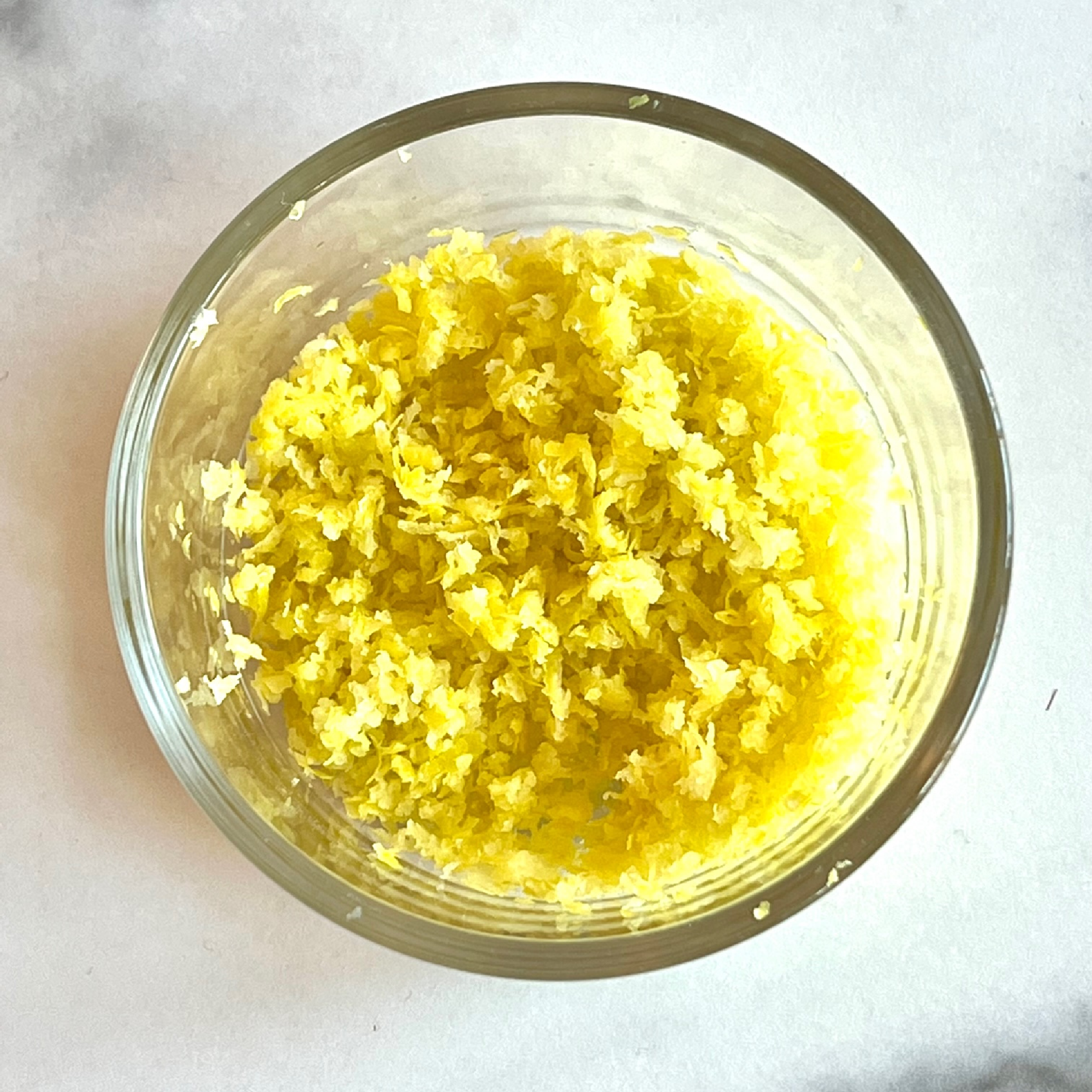 This is a photo of grated lemon peel in a small clear glass bowl. 