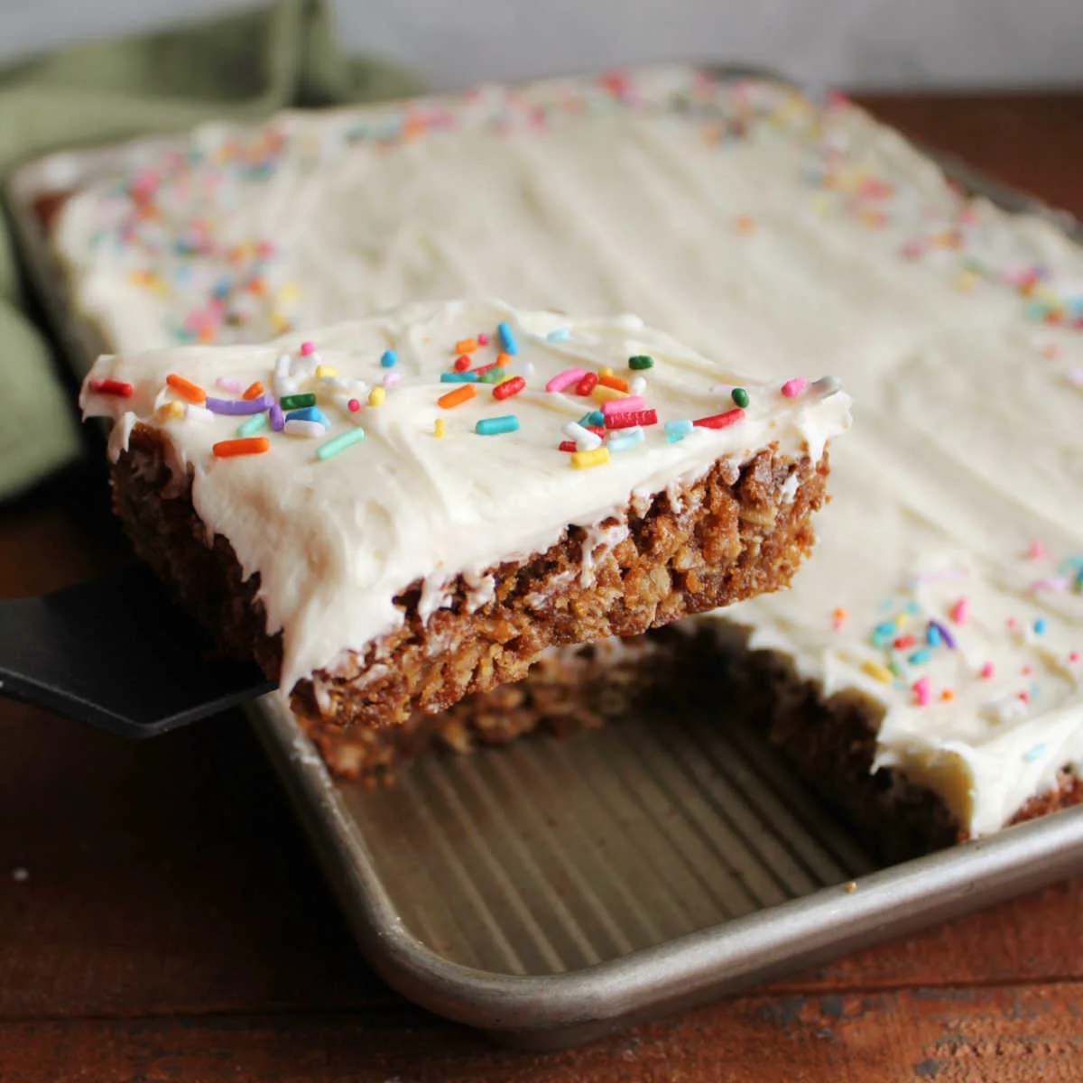 This image shows the oatmeal cream pie bars in the baking pan, with one bar being lifted by a spatula, ready to serve. 