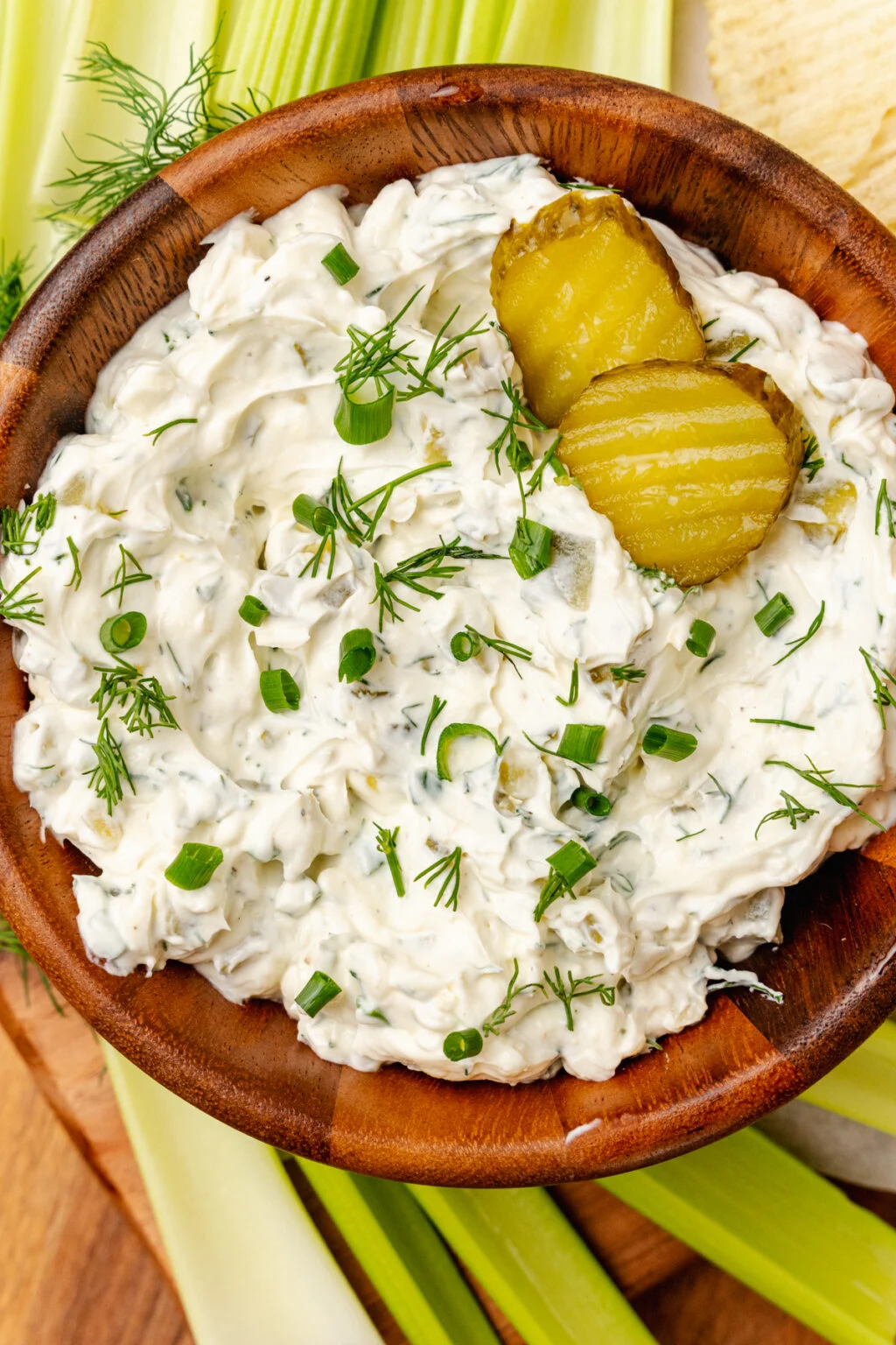 This photo shows a small wood bowl filled with dill pickle herb dip. 