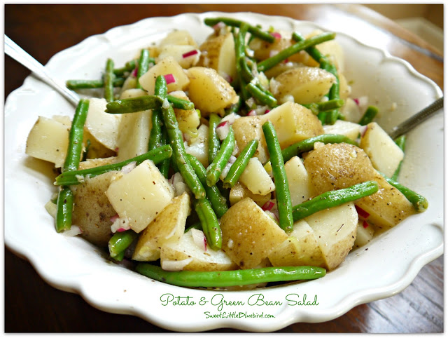 This photo shows potato and green bean salad served in a white bowl with a spoon.