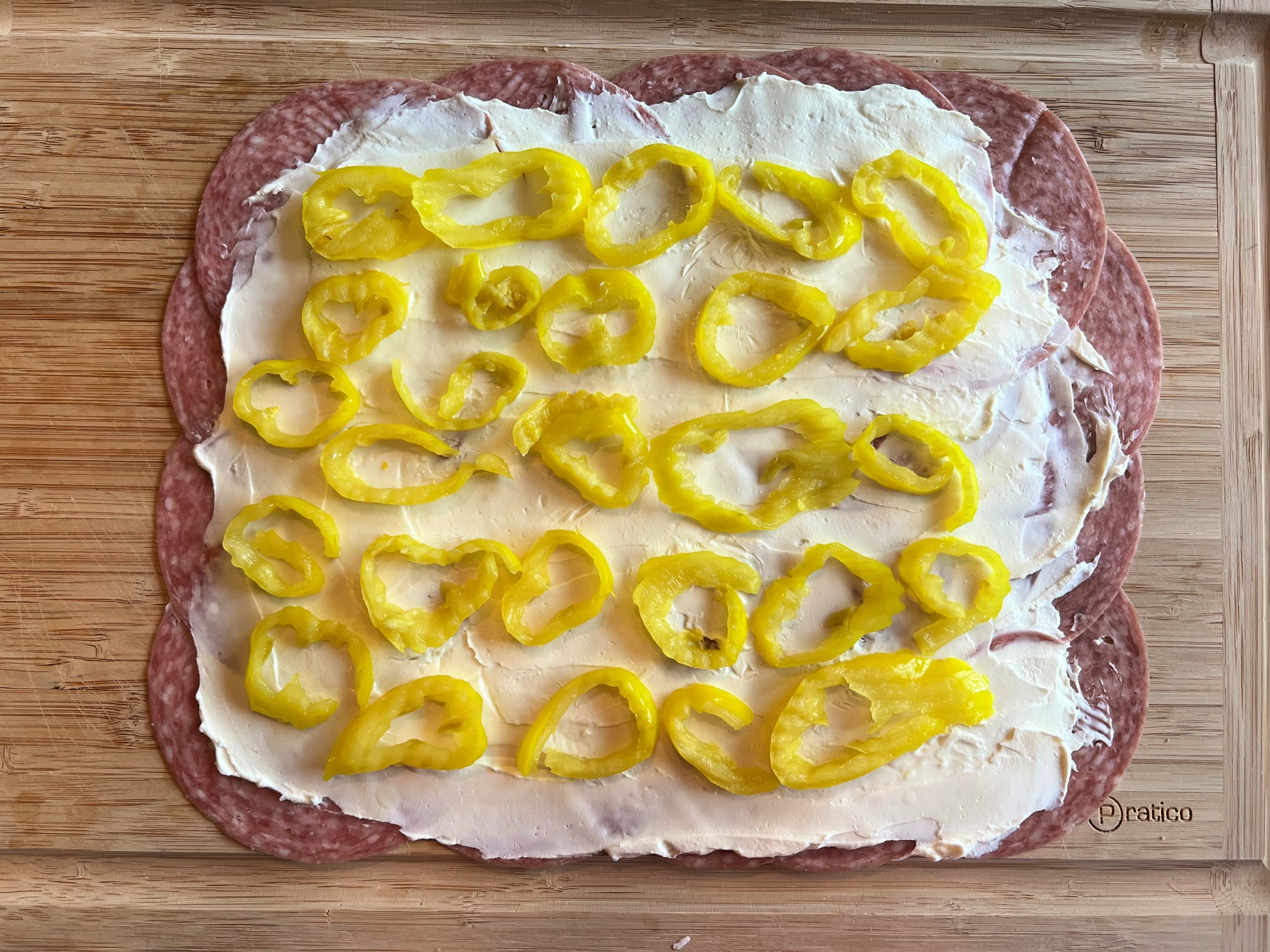 This photo shows the banana peppers placed evenly on top of the cream cheese and salami. 
