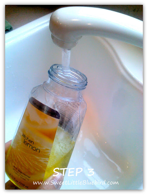 This photo shows the foaming soap dispenser being filled with water from a faucet in a kitchen sink.